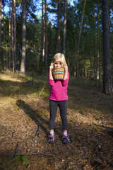 Cute little girl with wicker basket posing and walking through the woods. Summer holiday.

