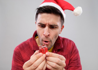 Closeup portrait unhappy, upset man holding small red gift