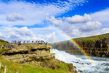 Fototapeta premium tourists watching rainbow on waterfall in Iceland