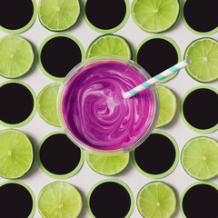 Pattern made of lime slices with purple smoothie.