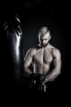 Male Athlete boxer punching a punching bag with dramatic edgy li