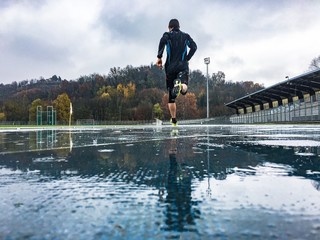  Man running on athletic track in a rainy day