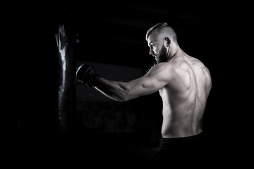 Fototapeta na wymiar Male Athlete boxer punching a punching bag with dramatic edgy li