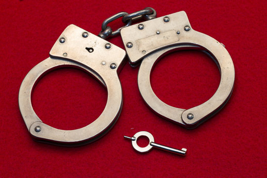 Metal Handcuffs on Red Background