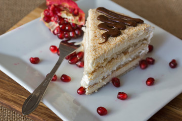 Portion homemade cream cake with pomegranate seeds and chocolate spread. Macro view. 