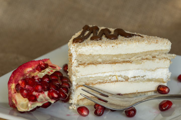 Portion homemade cream cake with pomegranate seeds and chocolate spread. Macro view. 