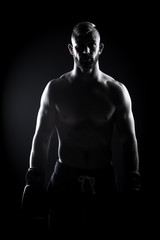 Obraz na płótnie Canvas Male Athlete boxer punching a punching bag with dramatic edgy li