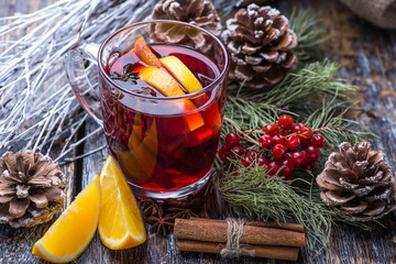 Hot drink, mulled red wine in a cup of glass on a wooden background