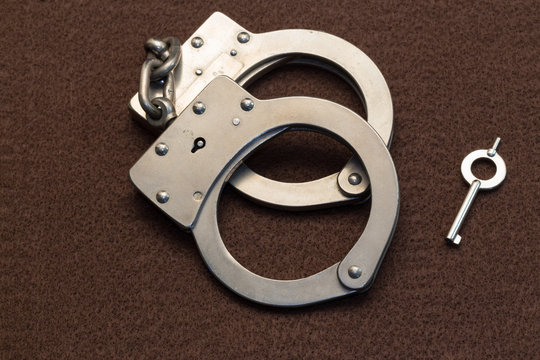 Metal Handcuffs on Brown Background