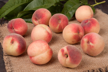 peaches in a wicker basket with leaves on wooden table