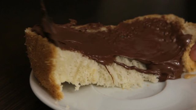Somebody smears freshly cooked bread with chocolate paste