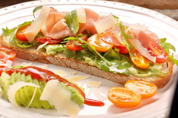 Avocado sandwich on fresh bread with arugula ham tomato and chee