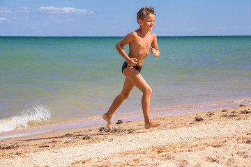 Fototapeta na wymiar Boy running from sea on beach