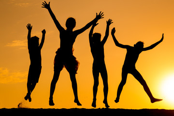 Fototapeta premium silhouette of four jumping kids against sunset