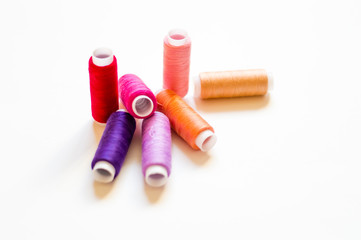 multicolored spools of thread on white background