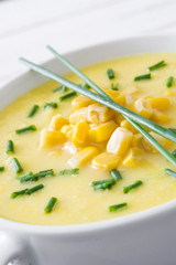 Corn soup in white bowl on wooden background.
