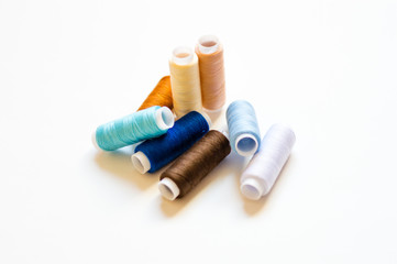 multicolored spools of thread on white background