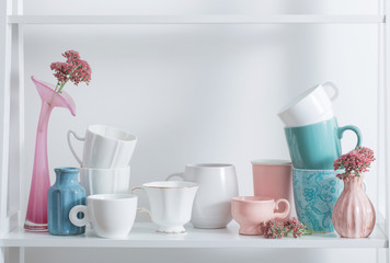 Clean dishes and flowers on wooden shelf