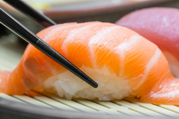 Salmon sushi with chopsticks black