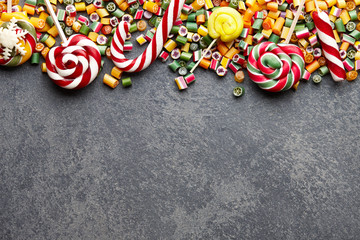 Colorful lollipops, candy canes and sweet candies mix on dark stone background
