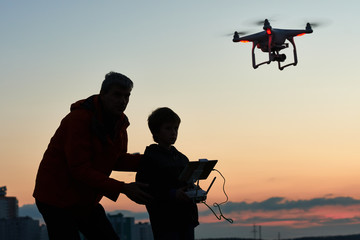 man operating of flying drone at sunset - obrazy, fototapety, plakaty