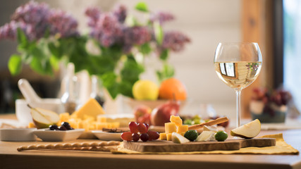 glass of white wine with a snacks stand on the kitchen table - 127953358