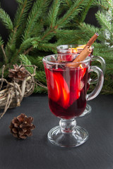 Christmas tradition drink. Hot Mulled wine with cinnamon and christmas tree on black slate dish. New Year. Holiday card. Close up, copy space.