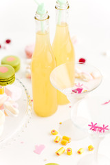 Two glasses and bottle of lemonade on table with sweets