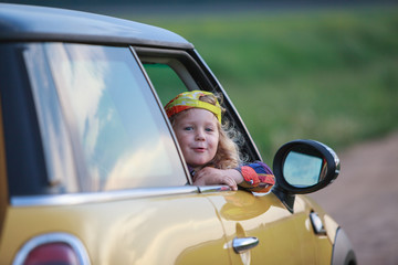 Little boy looking out from the yellow car. Kid traveling. Happy child on vacation. 
