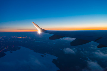 Fototapeta na wymiar aircraft wing with light and winglet at dusk with frozen lake below 
