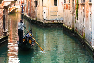 Fototapeta na wymiar Through the canals of Venice. A Venetian gondolier propels a gondola.