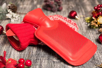 Hot water bottle on the background. Red bag with water on wooden table