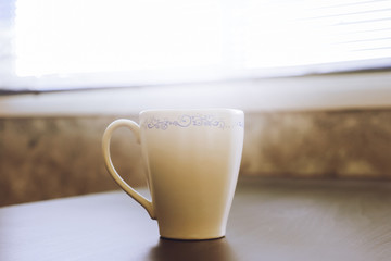 A cup of cofee on the table,toned with sunlight.