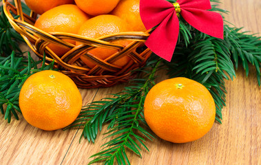Ripe tangerines in the wicker basket, a sprig of tree with red bow