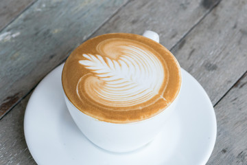 A Cup of hot latte art coffee on wooden table
