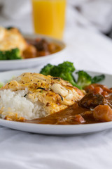 Japanese curry on rice with egg vegetable and orange juice at the back