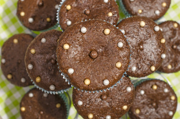 Chocolate muffins in a cute holder.A pile of cacao muffins with candy on top.