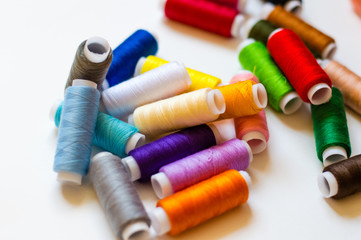 multicolored spools of thread on white background