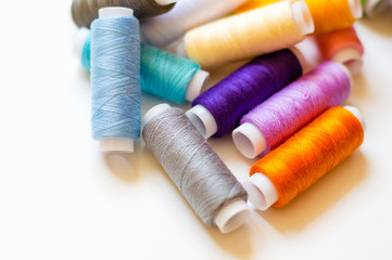 multicolored spools of thread on white background