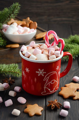 Obraz na płótnie Canvas Hot chocolate with marshmallows and candy canes on dark wooden background. Holiday concept, selective focus, vertical with copy space.