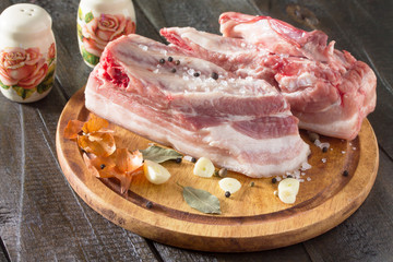Salty lard with spices and parsley on a wooden background.