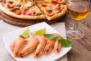 Big tasty pizza with seafood, tomatoes, wine on wooden table