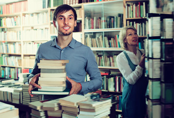 Smiling man having book pile in hands