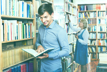 Young smiling man reading book while