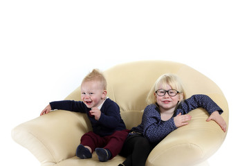 Śliczne rodzeństwo, brat i siostra bawią się na fotelu.