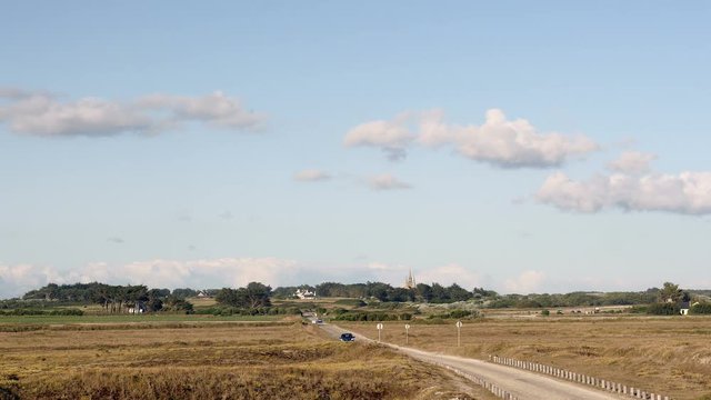Little road and landscape with village in background in Brittany, France, on a beautiful summer day.