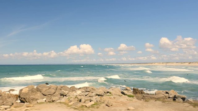Waves at Pointe de la Torche in Brittany, France on a summer day. Pan from ocean to beach and coastal line.