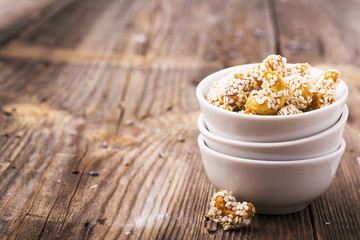 Roasted cashew nuts coated with a honey glaze and sprinkled  white sesame seeds in  ceramic dishes  la carte on  simple wooden background. Garnish to the cheese plate appetizer, aperitif, in