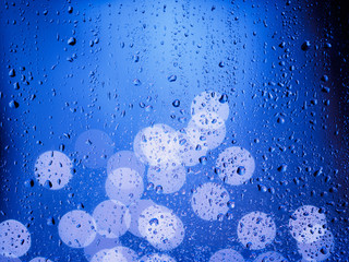 Rain drops on window glass with bokeh lights in background