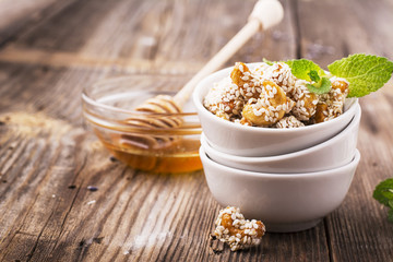 Roasted cashew nuts coated with a honey glaze and sprinkled  white sesame seeds in  ceramic dishes  la carte on  simple wooden background. Garnish to the cheese plate appetizer, aperitif, in